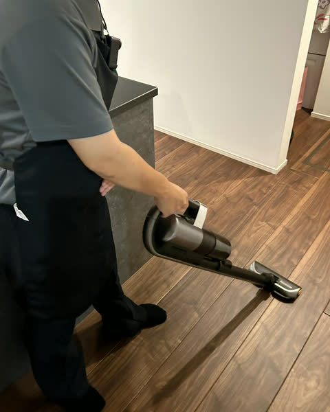 フローリングに掃除機をかけるスタッフ